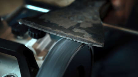 Asian man sharpening axe on a grinderの写真素材