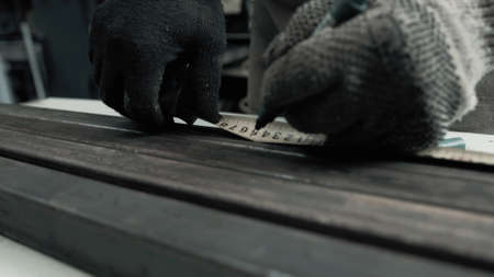 Man with gloves measures metal beams with a meterの写真素材