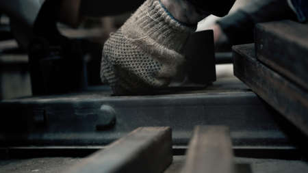 A worker with gloves tightens the bolts in a metal machine