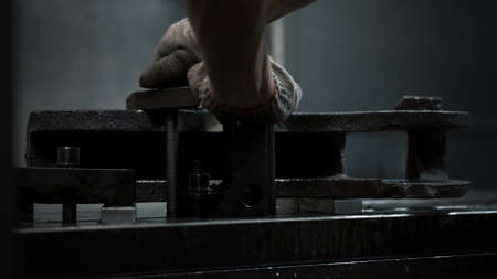 Worker installs a metal workpiece in the machine