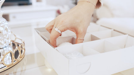 The girl takes beautiful shiny Christmas toys from the boxの写真素材