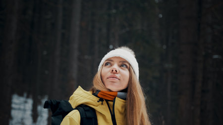 Girl with a white hat in the forest with a backpack in winter. Side view. Close upの写真素材