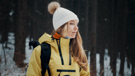 Girl with a white hat in the forest with a backpack in winter. Side view. Close upの写真素材