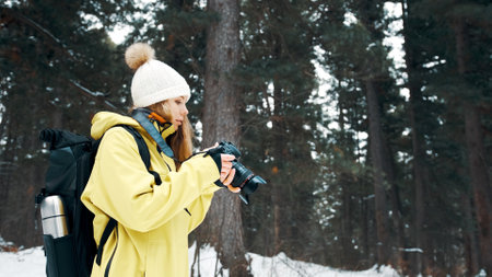A girl with a backpack and a yellow anorak photographs the landscape on a professional cameraの写真素材