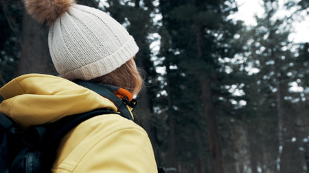 A girl with a backpack and a yellow anorak photographs the landscape on a professional cameraの写真素材