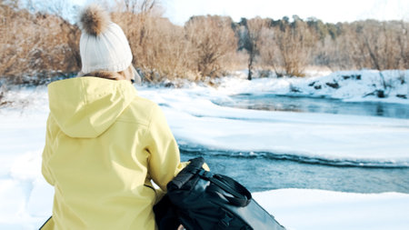 The girl sits in the lotus position in the winter in the forest and looks at the riverの写真素材