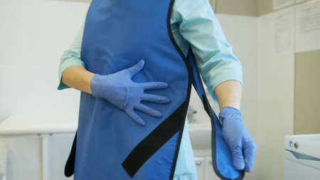 Woman puts on a protective mask and suit. Protected against flu, ebola, tuberculosis, virus. Personal protective equipment against biological hazard.の写真素材