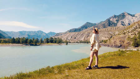 Girl wearing beige outfit on the hill looking over to wonderful mountain view. Drone footageの写真素材
