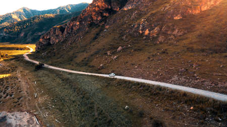 White car drives through narrow road in the mountains. Drone footageの写真素材