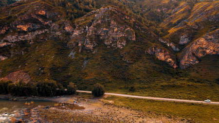 White car drives through narrow road in the mountains. Drone footageの写真素材