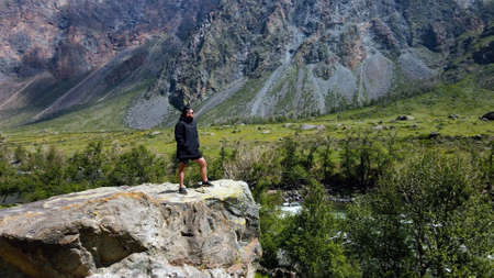 A man stay on the edge of a cliff wearing a black anorak. Katu-Yaryk canyon Chulyshman Valley. Altaiの写真素材