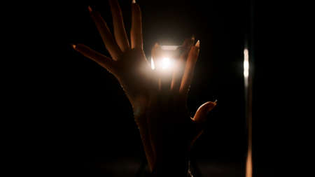 The girls hands against the background of the hard light of the back. Close-up, black background