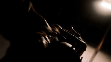 A sexy girl hugs her neck in a backlight with her hands. Black background. Close-up of the handsの写真素材