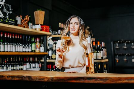 Young elegant woman with the glass of wine near the bar countertop.の写真素材