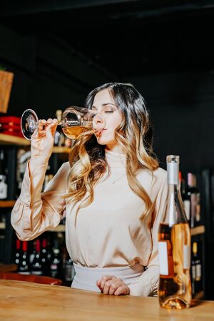 Young elegant woman with the glass of wine near the bar countertop.の写真素材