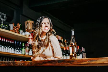 Young elegant woman with the glass of wine near the bar countertop.の写真素材