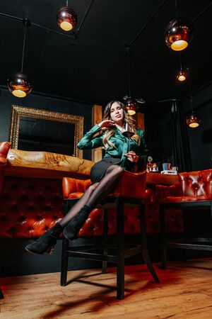 Young elegant woman with the glass of wine near the bar countertop.の写真素材
