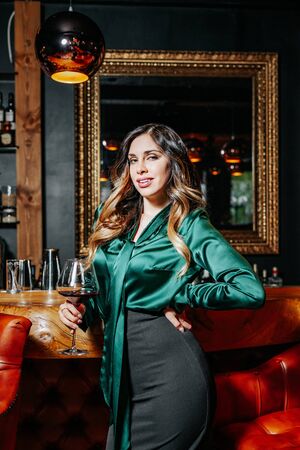 Young elegant woman with the glass of wine near the bar countertop.の写真素材