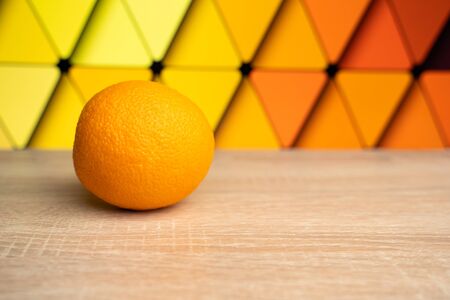 orange on a wooden table on a colored backgroundの写真素材