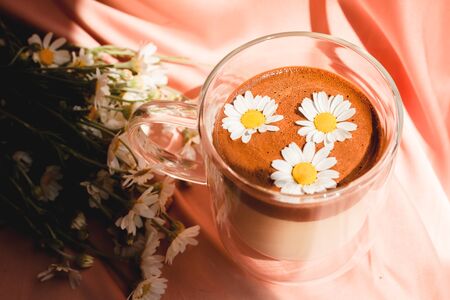 Tasty cup of coffee on a pastel background. Bouquet of chamomiles, sunny day, morning. Blooming Wild Flower Matricaria Chamomilla Or Matricaria Recutita Or Chamomile.の写真素材