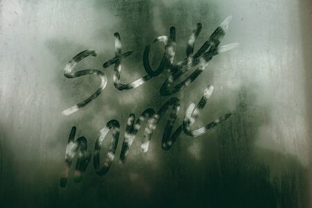The inscription "stay home" on the foggy window. Cloudy and rainy weather.の写真素材