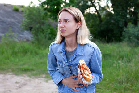A young woman is holding a large burger.の写真素材