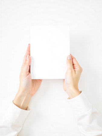 Woman's hands holding a blank white paper sheet on a white backgroundの素材