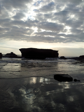 Reflections of rock with dramatic clouds along a beachの写真素材