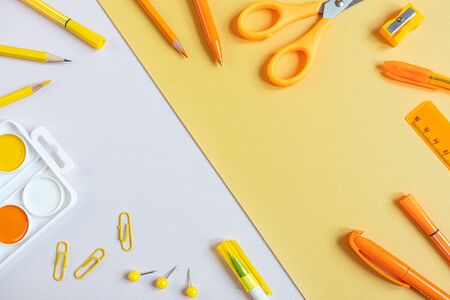 Concept back to school. School stationery flat lay: watercolor, pens, pencils, sharpener, scissors, ruler, paper clips on yellow and gray background. Orange and yellow tones. Copyspace.の写真素材
