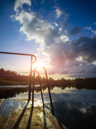Summer landscape: the sky with clouds and the forest on the horizon are reflected in the clear water...