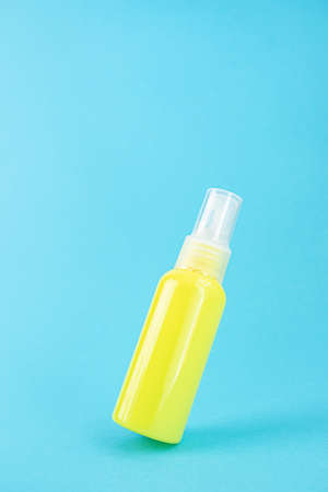 Yellow cosmetic bottle on a blue background. Stylish concept of organic essences, beauty and health products. Copy space, minimalism, levitation effect.の写真素材