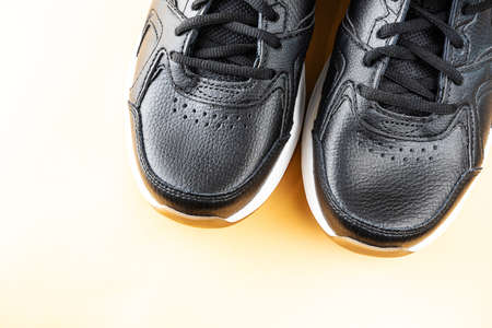 Black sports leather sneakers close up. Comfortable casual shoes concept. Light background, copy space.の写真素材