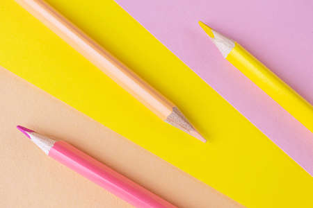 Back to school. Pink and yellow pencils lie on the same colors background. Creative minimalistic concept of children's creativity, drawing.の写真素材