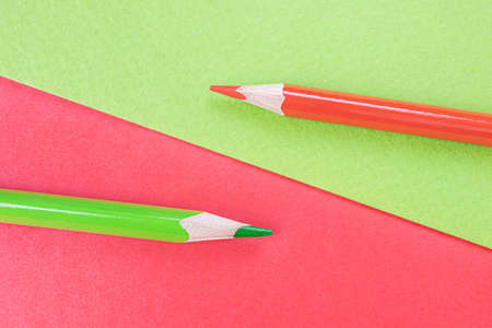 Back to school. Red and green pencils lie on the background of the same colors. Creative minimalistic concept of children's creativity, drawing.の写真素材