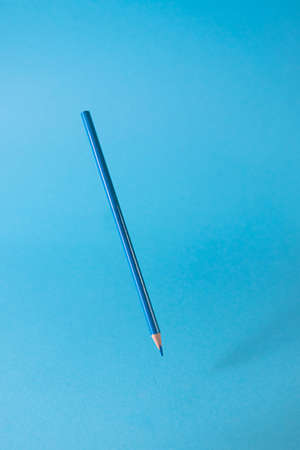 Back to school. A blue pencil stands on a blue background. Monochrome image. Creative concept of...