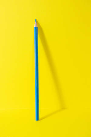 Back to school. A blue pencil stands on a yellow background. Creative minimalistic concept of children's creativity, drawing.の写真素材