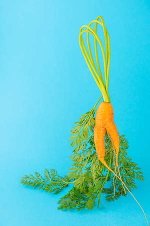 Strange funny shaped carrots on a blue background. Vegetable crops concept. Minimalism, copy space. Ugly carrot.の写真素材