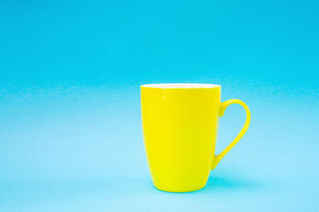 Yellow cup on a blue background. Minimalism, copy space.