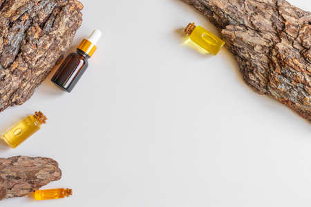 Bottles of natural essential oil and tree bark with a beautiful texture. Neutral background. Concept for natural essences, organic cosmetics, aromatherapy, spa. Flat lay, copy space, top view.の写真素材
