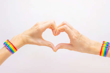 Women's hands in a bracelet in rainbow colors LGBT folded in the shape of a heart. The concept of...