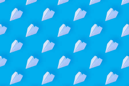 Pattern from white paper airplanes on a blue background. Creative concept of travel, flights.
