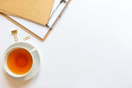 Home workspace: craft notebook, pencil, cup of tea, paper clips. Cozy flat lay in pastel colors, feed on top, copy space.の写真素材