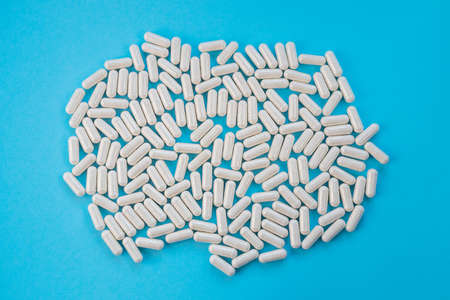 Light capsules are scattered on a blue background. The concept of vitamins, dietary supplements....