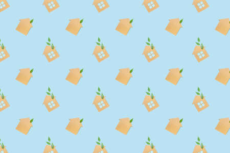 Houses made of craft paper and green leaves of a plant on a light blue background. Eco-friendly home...