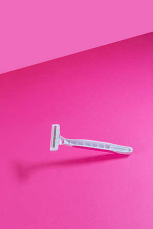 Women's plastic razor on a bright pink isothermal background. Trending concept of plastic-free.