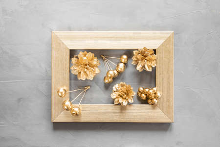 New Year's flat lay in golden and gray shades. Frame, stars, cones and berries are painted with golden paint. Stylish concept of christmas, celebration. Top view, minimalism, copy space.の写真素材