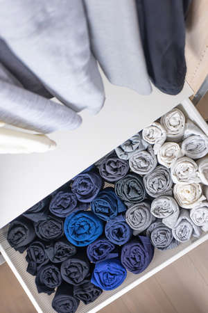 The concept of organizing space in the wardrobe. Clothes of dark and light shades hang neatly and...