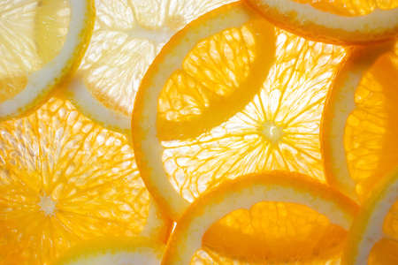 Orange and lemon wedges illuminated from below. Bright citrus background. Concept of healthy...
