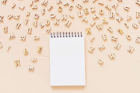 Notepad with an open blank page and wooden English letters on a light surface. Concept for alphabet, writing and journalism, storytelling, learning.の写真素材