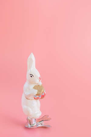 Old vintage Christmas toy - bunny with a drum. Festive new year concept, pastel pink background. Minimalism. XX century, antiques.の写真素材